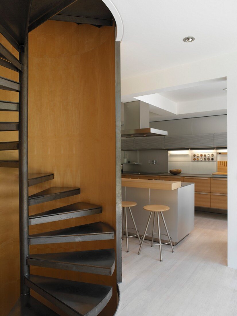 Spiral staircase with kitchen counter and bar stools in background