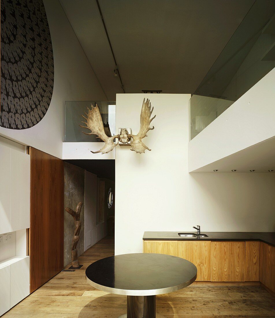 Gallery and open-plan kitchen with round table & antlers
