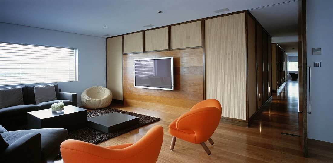 Wohnzimmer mit Sofa, orangefarbenen Sesseln & Fernseher