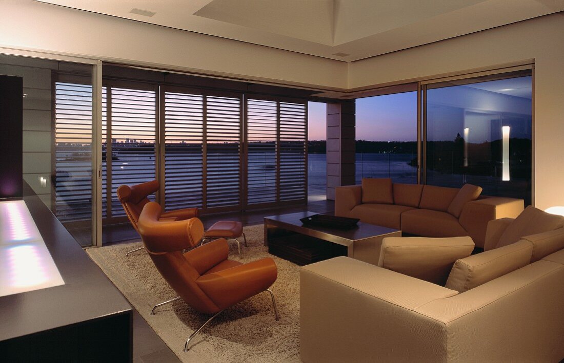 Wohnzimmer mit Sofa, Sesseln, Couchtisch & Lamellen-Schiebetüren zur Terrasse