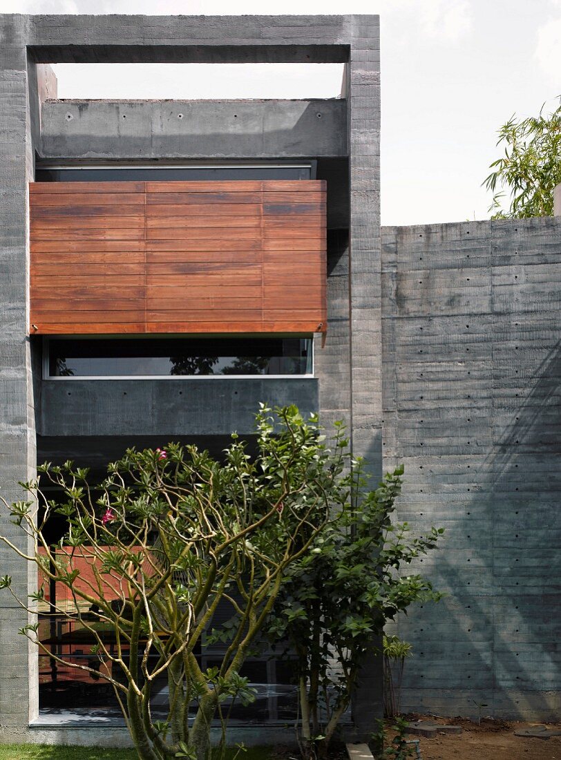 Wohnhaus mit Betonfassade und Holzverkleidung vor Fenstern