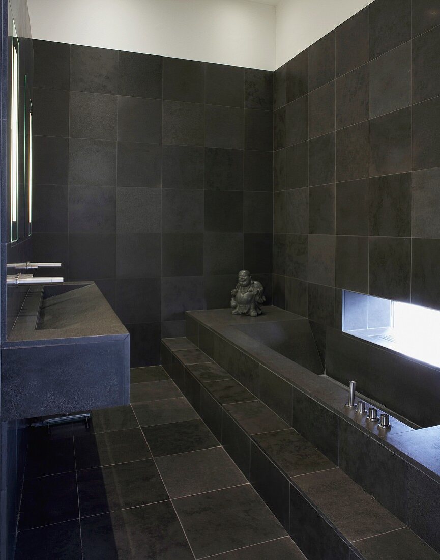 Bathroom tiled in dark grey with bathtub & sink