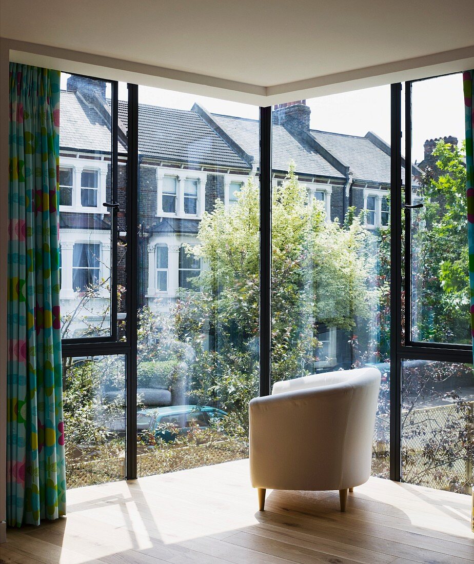 Upholstered armchair in front of glass facade of house