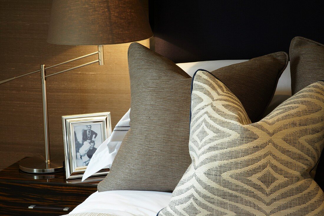 Scatter cushions on bed next to bedside table