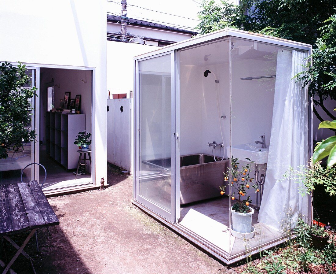 Part glass container with bathroom appliances situated in garden
