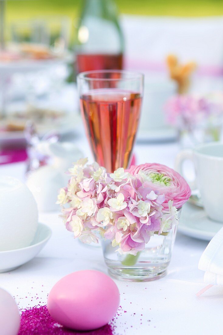 Rosa Tischdekoration mit Hortensien, Ei und einem Glas Sekt