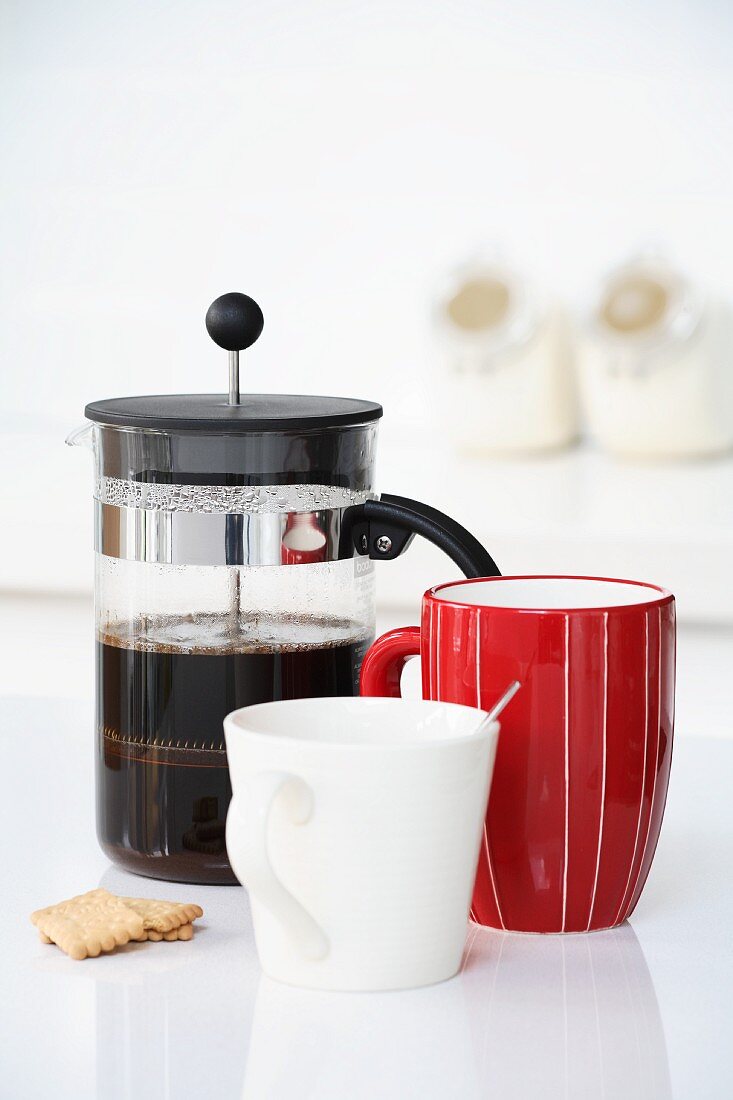 Coffee in cafetiere, red mug and white cup