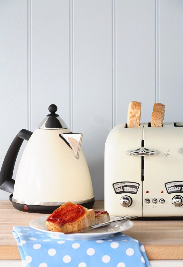 Toastscheibe mit Marmelade, Wasserkocher und Toaster
