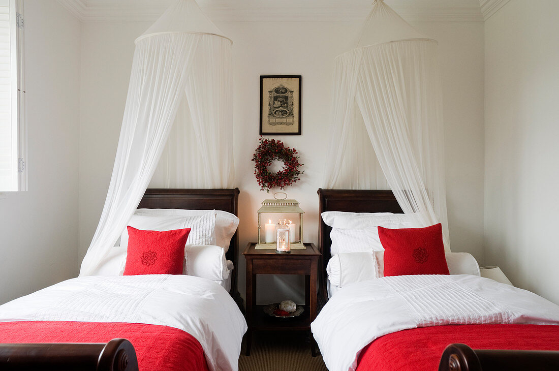 Einzelbetten mit Baldachin und rotem Kissen in minimalistischem Schlafzimmer