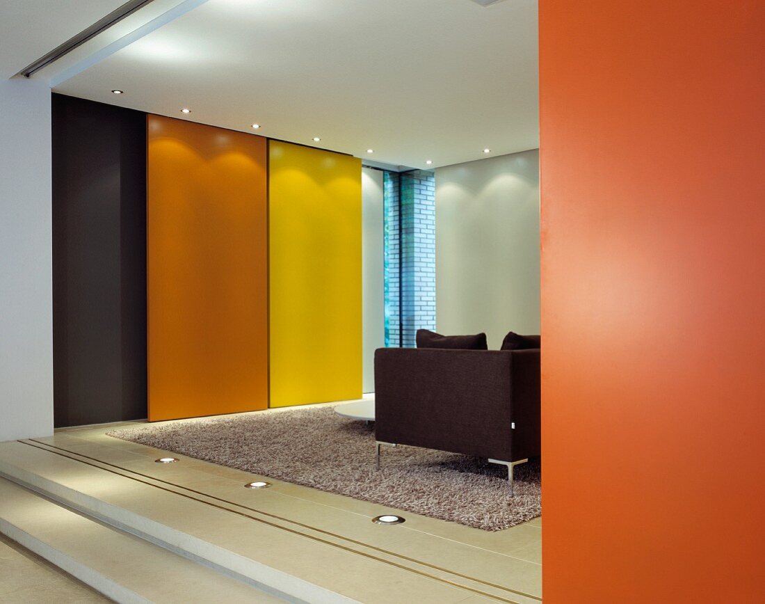 Colourful sliding walls in front of floor-to-ceiling windows in modern living space