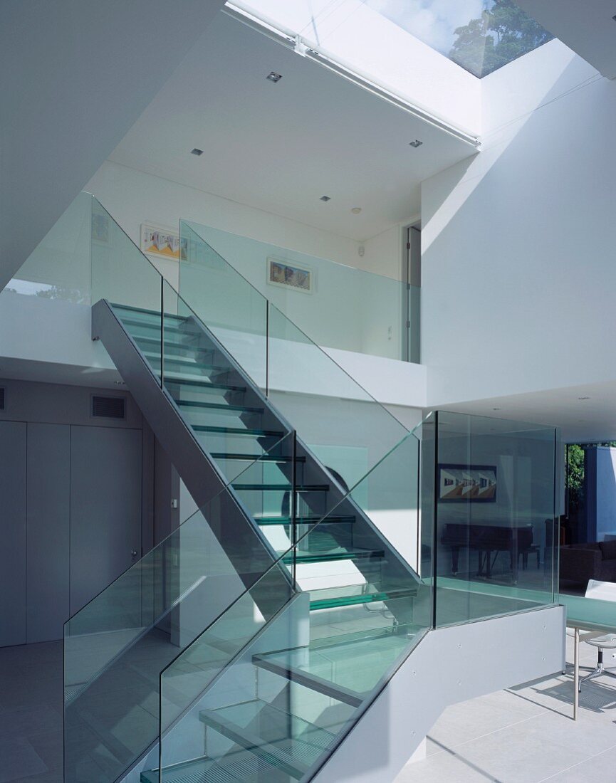 Eine Treppe mit Glasgeländer führt vom Wohnbereich zum Obergeschoss
