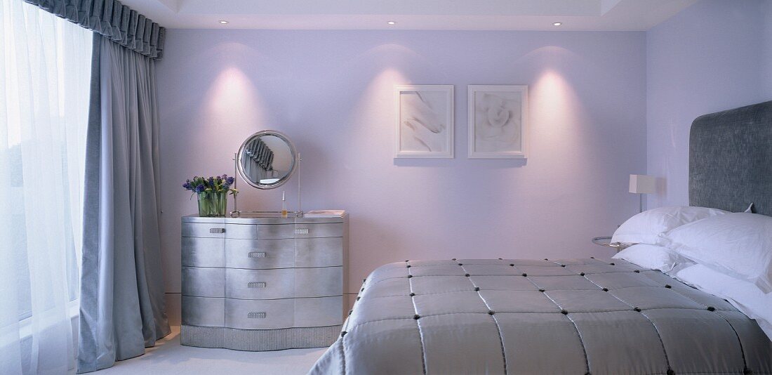 Schlafzimmer mit silberner Kommode und silbernen Wohntextilien ausgestattet