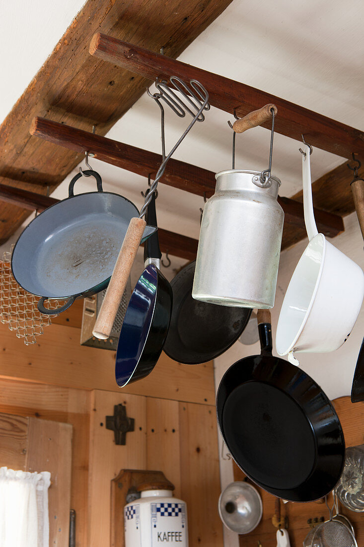 Vintage cooking equipment and a tin milk churn hanging from a wooden frame under the ceiling