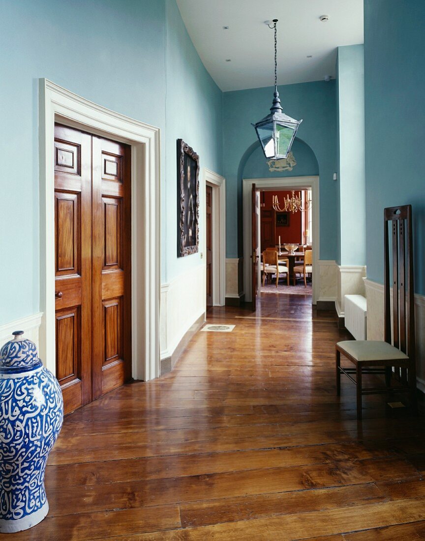 Hellblau getönter traditioneller Flur mit chinesischer Bodenvase neben Holzflügeltür