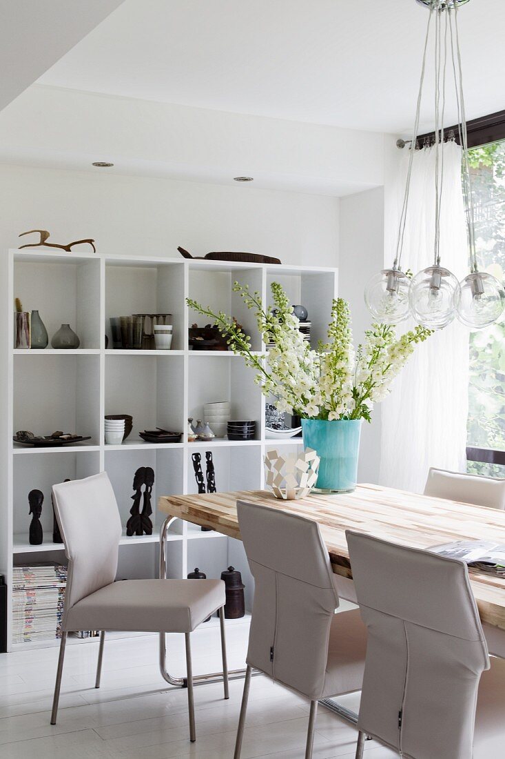 White, leather-covered chairs at modern table opposite shelving