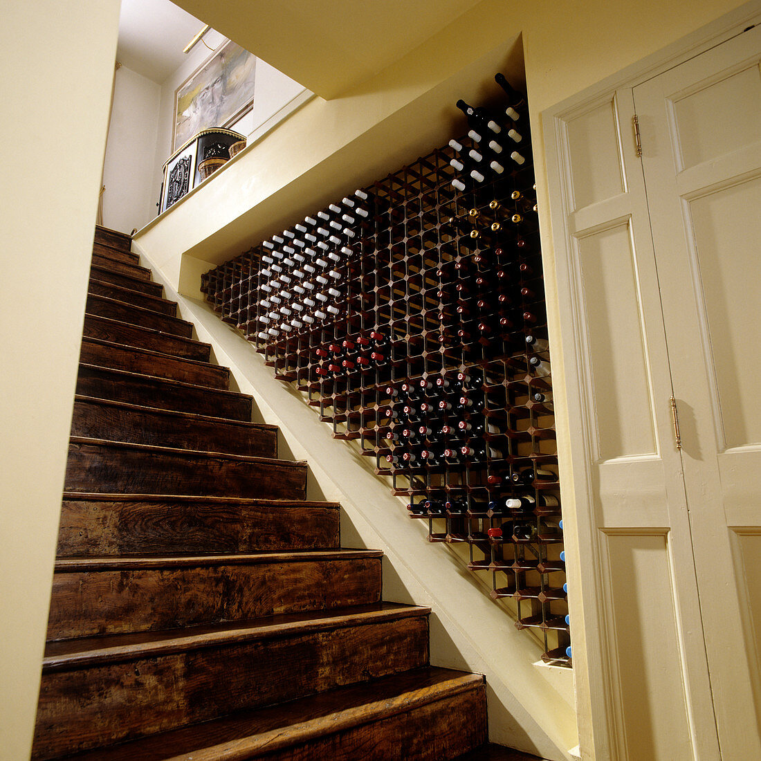 Alte Holztreppe entlang einer Wandnische mit integriertem Weinregal