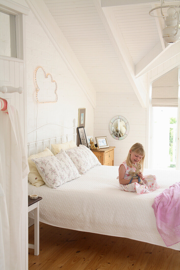 Child playing on bed in bright attic bedroom