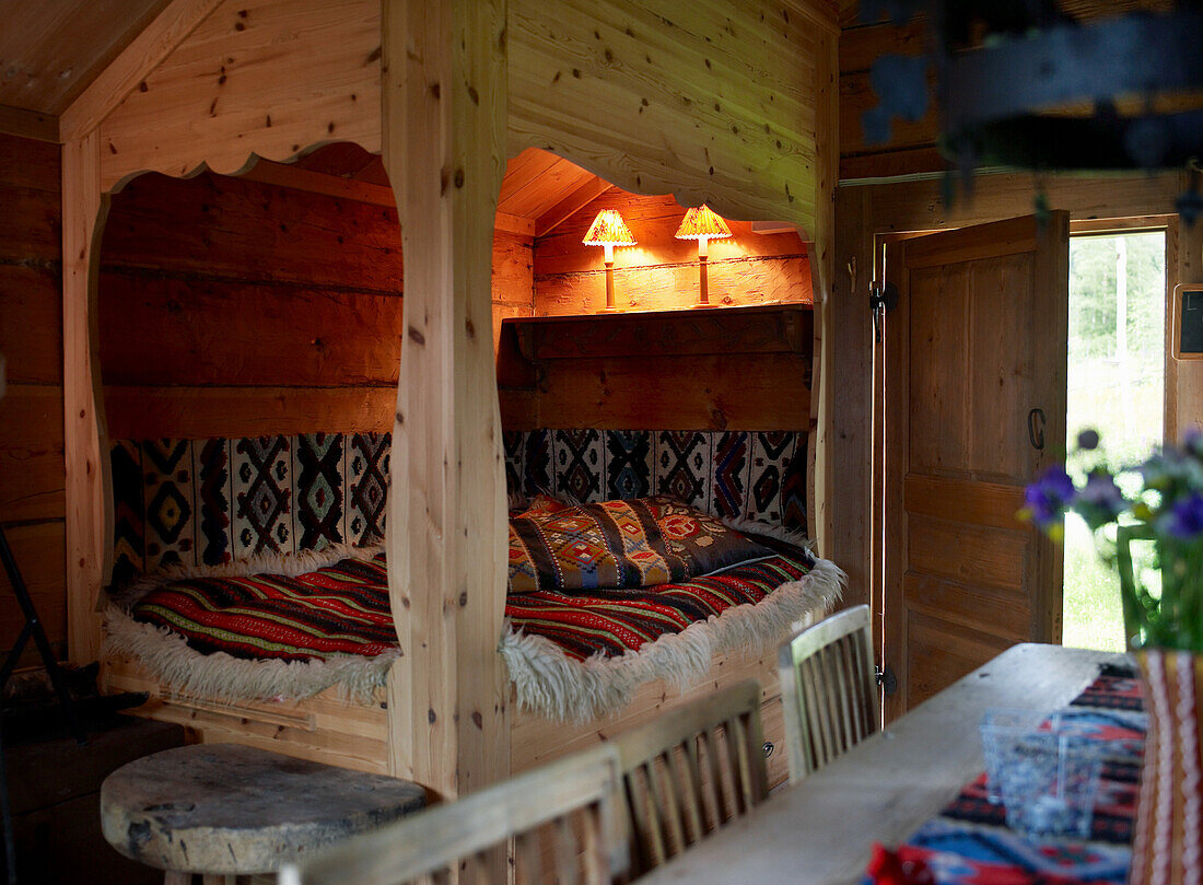 Holzbett mit gemusterter Decke und gemusterten Kissen in rustikaler Hütte