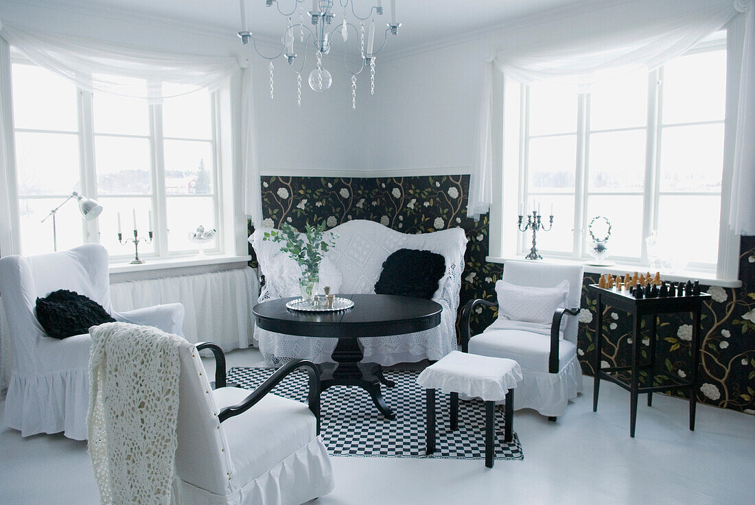 Helles Wohnzimmer mit schwarz-weißem Interieur und Kristallleuchter