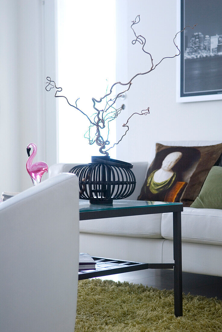 Delicate hazel twig in crude iron basket on coffee table in modern living room