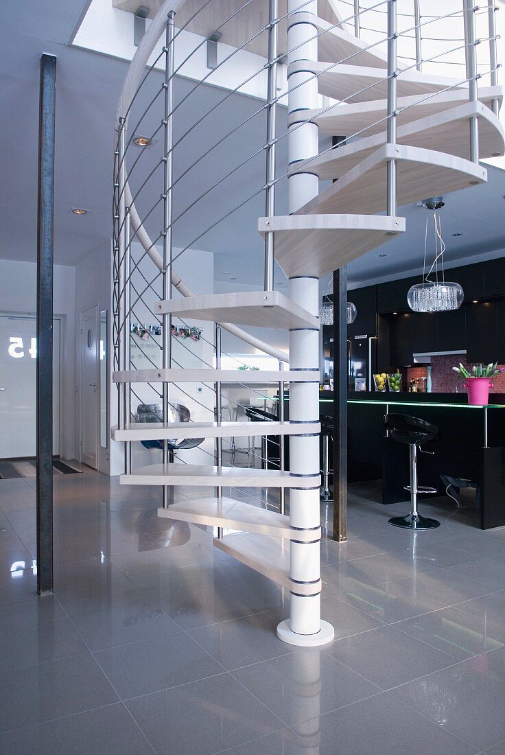 Moderne Wendeltreppe in offenem Wohnbereich vor schwarzer Designerküche