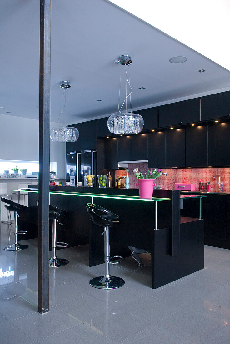 Black designer kitchen with breakfast bar in open-plan living area