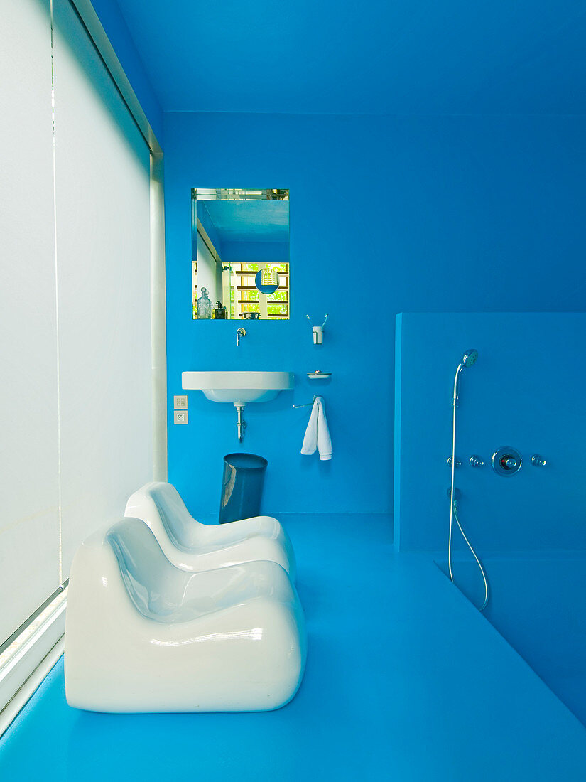 Azure blue bathroom with white plastic chairs in front of window with closed panel blinds