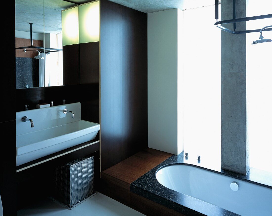 Designtes Bad mit Holzverkleidung an Wand und im Boden eingelassener Badewanne