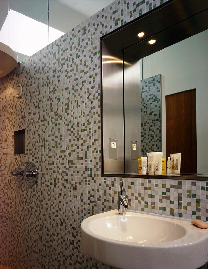 Bad mit Waschtisch und Spiegel an Wand mit Mosaikfliesen