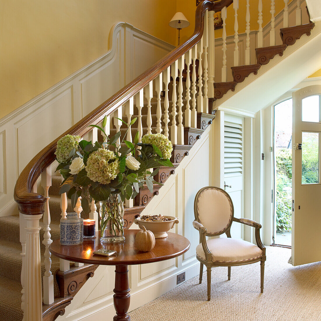 Entrance area with wooden staircase, floral decorations and classic chair