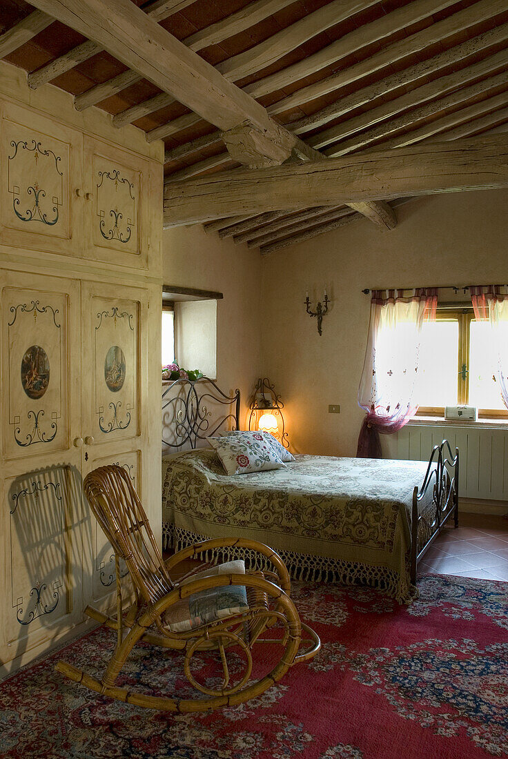 Country bedroom with wrought iron bed and wooden beamed ceiling