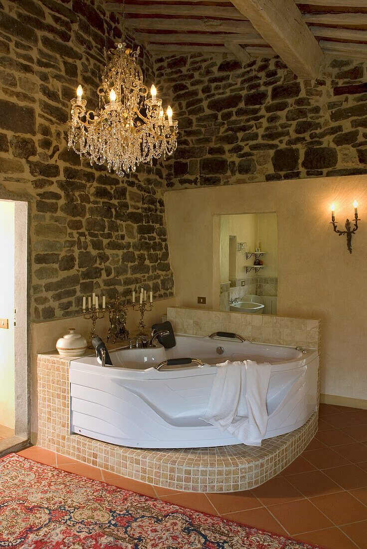 Whirlpool in rustic bathroom with chandelier