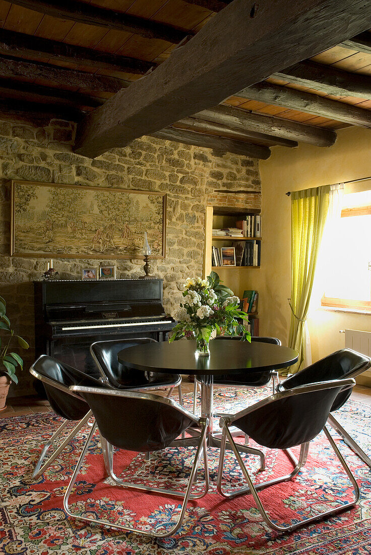 Rustic dining area with black tulip chairs and round table on oriental carpet