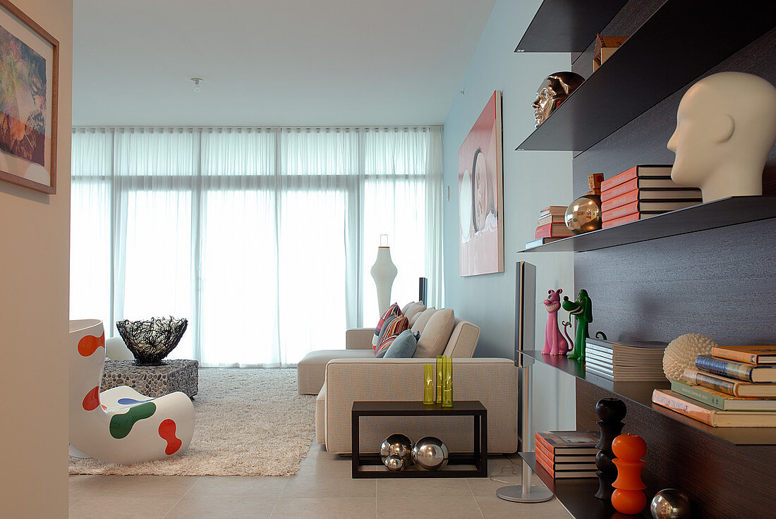 Wohnzimmerdeko mit modernen Designobjekten - elegant schwebendes Wandregal und helle Sitzgruppe im Hintergrund