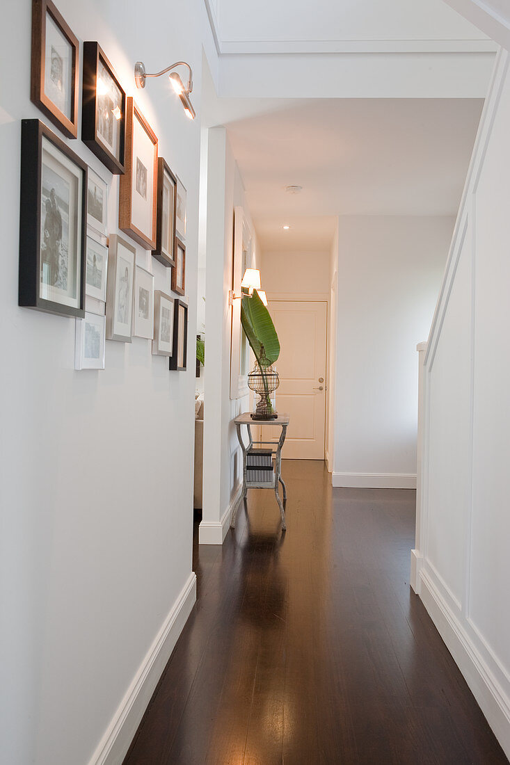 Console table below illuminated mirror in traditional stairwell with dark wooden floor