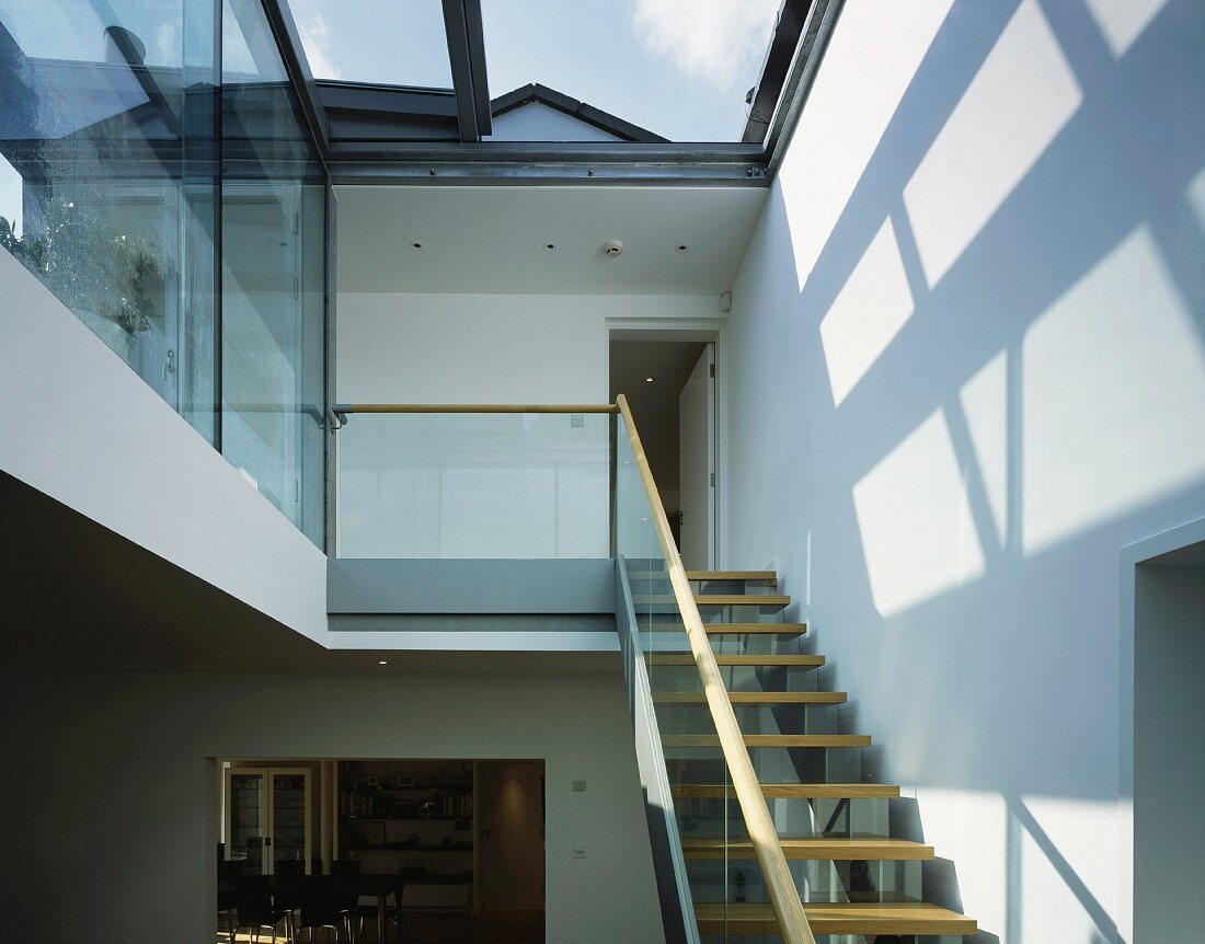 Treppenaufgang unter Glasdach und Lichtspiele an der Wand