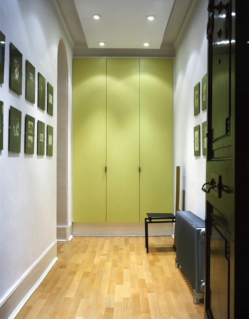 Brightly-lit, modernised hallway with fitted cupboards and green-painted doors