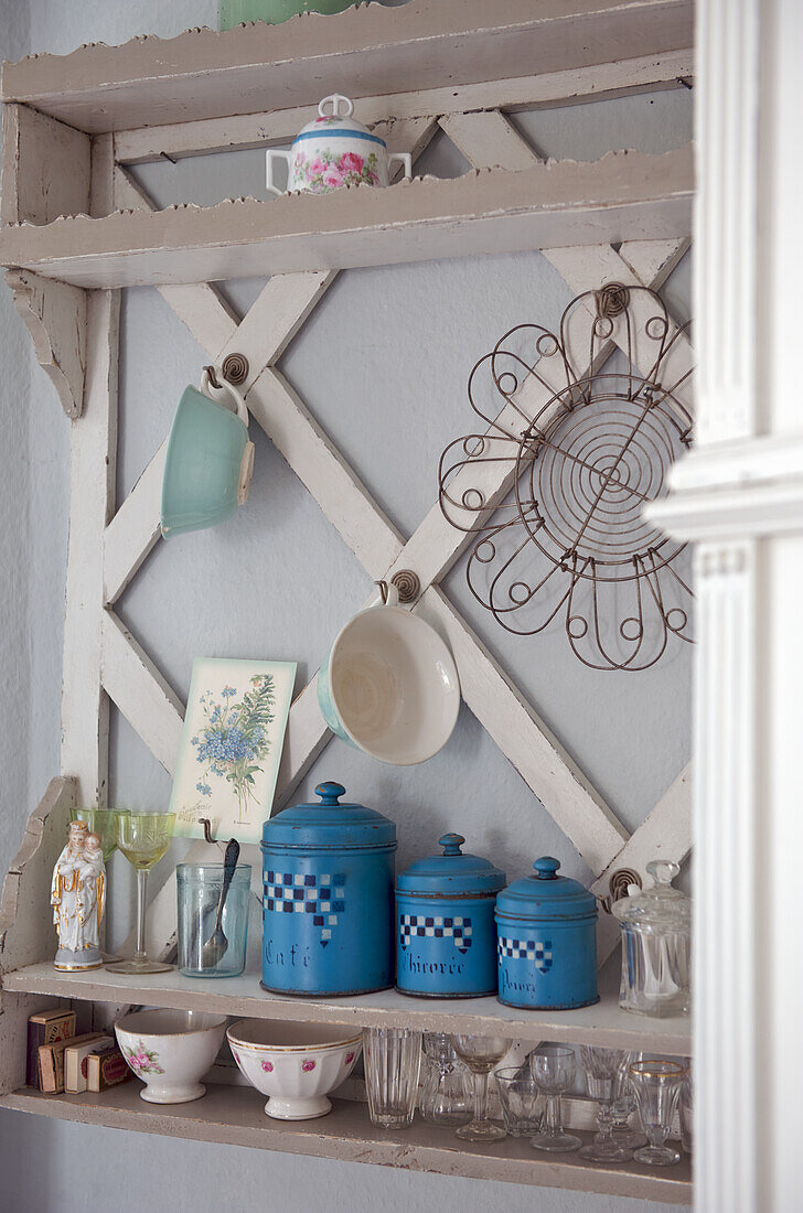 Vintage shelf with decorative items and blue kitchen canisters on the wall