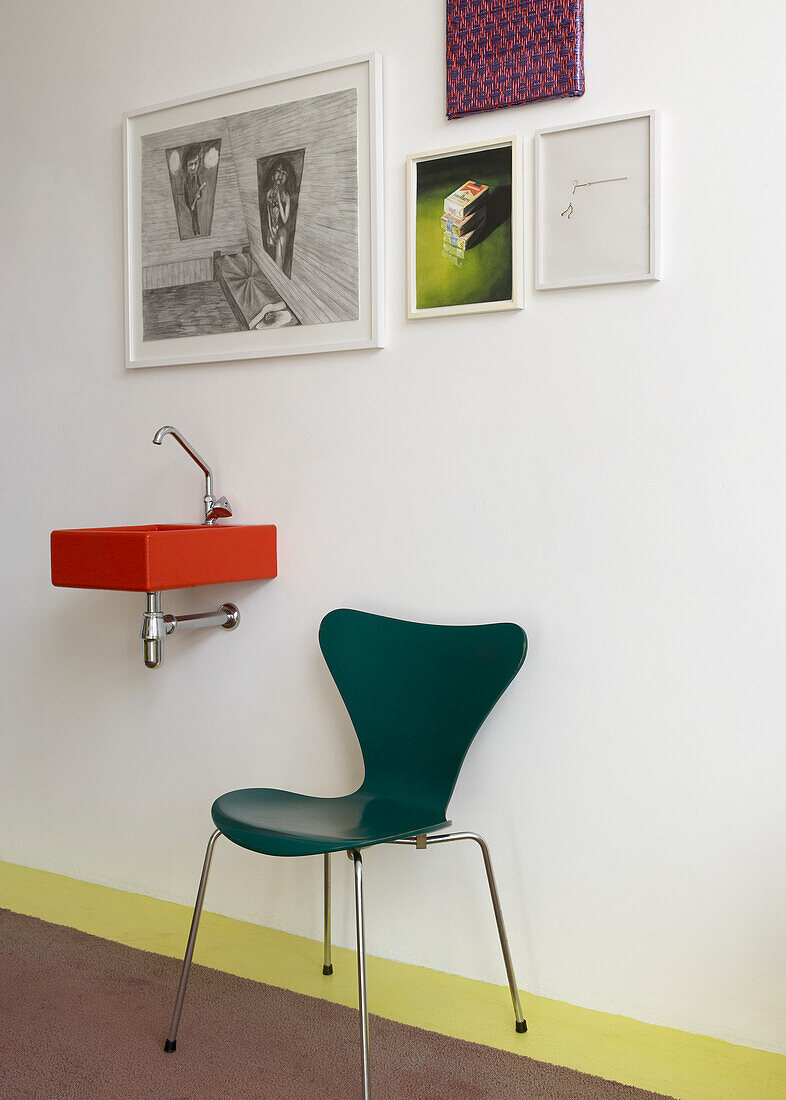 Wall-mounted washbasin, pictures and green chair