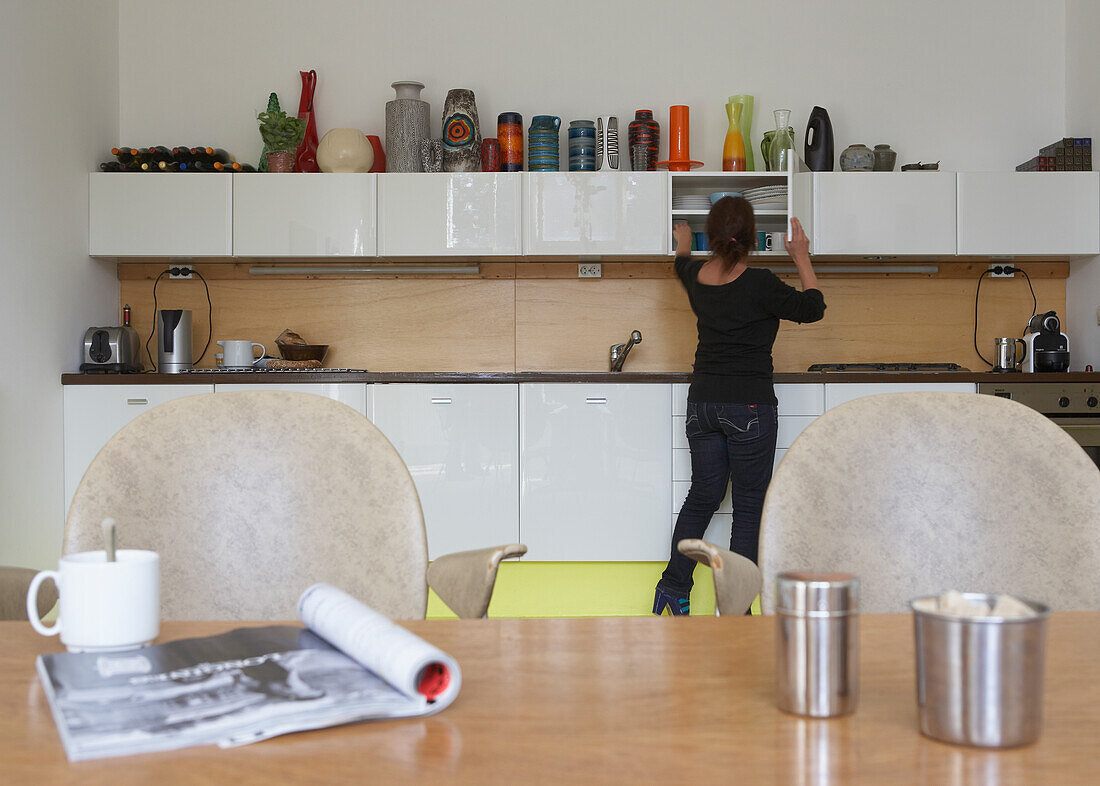 Woman putting away kitchen cupboard