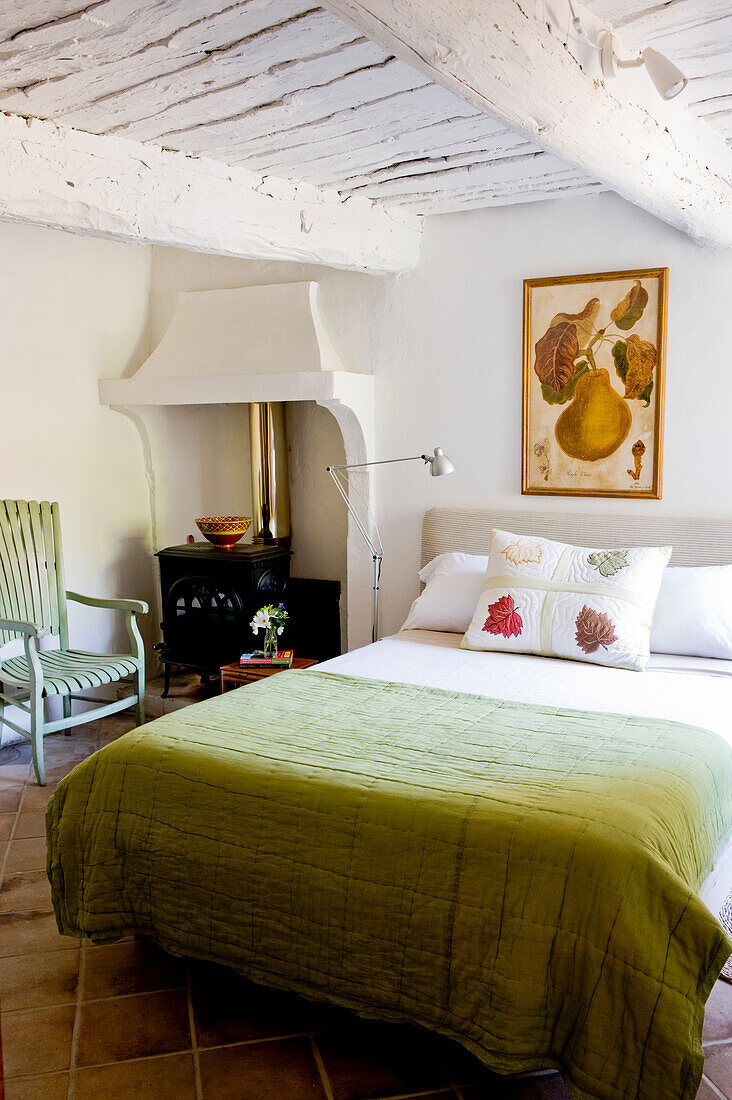 Country-style bedroom with green bedspread and fireplace