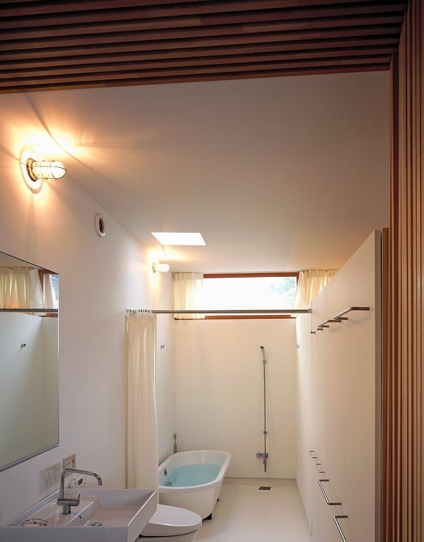 View into white bathroom with shower and bath area separated by curtain