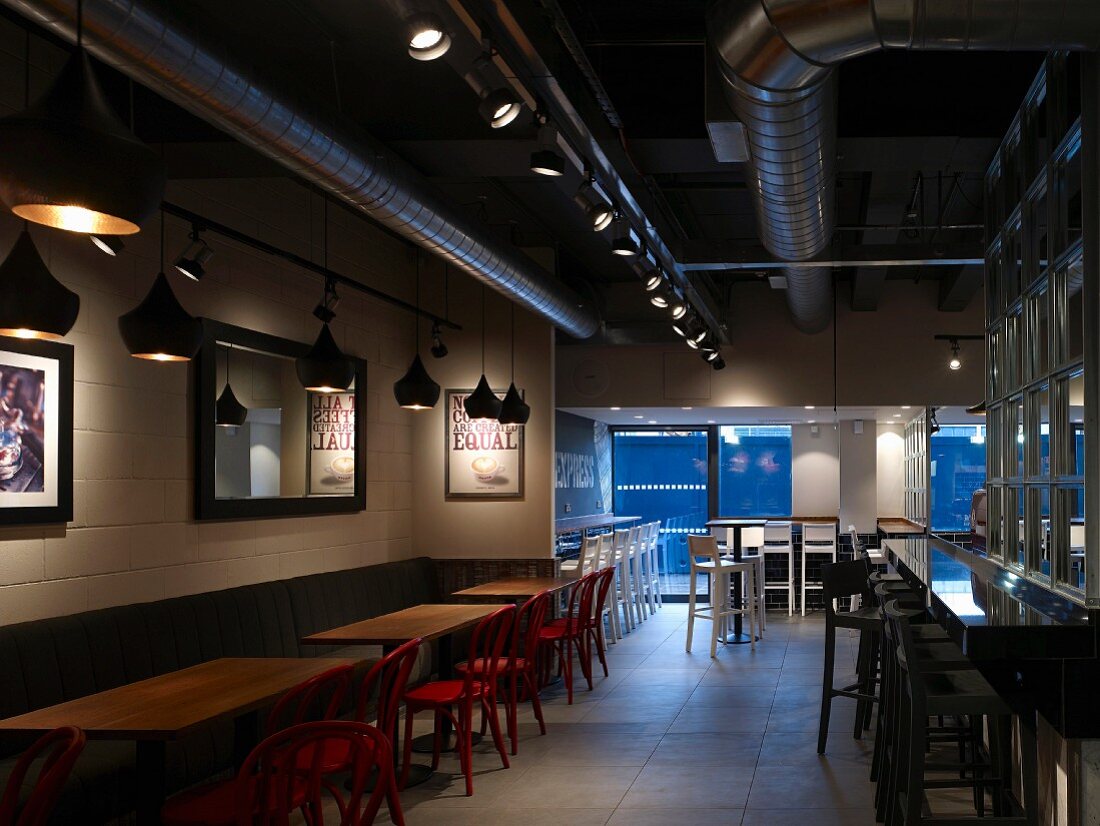 Cafe with long counter and wooden tables with red chairs