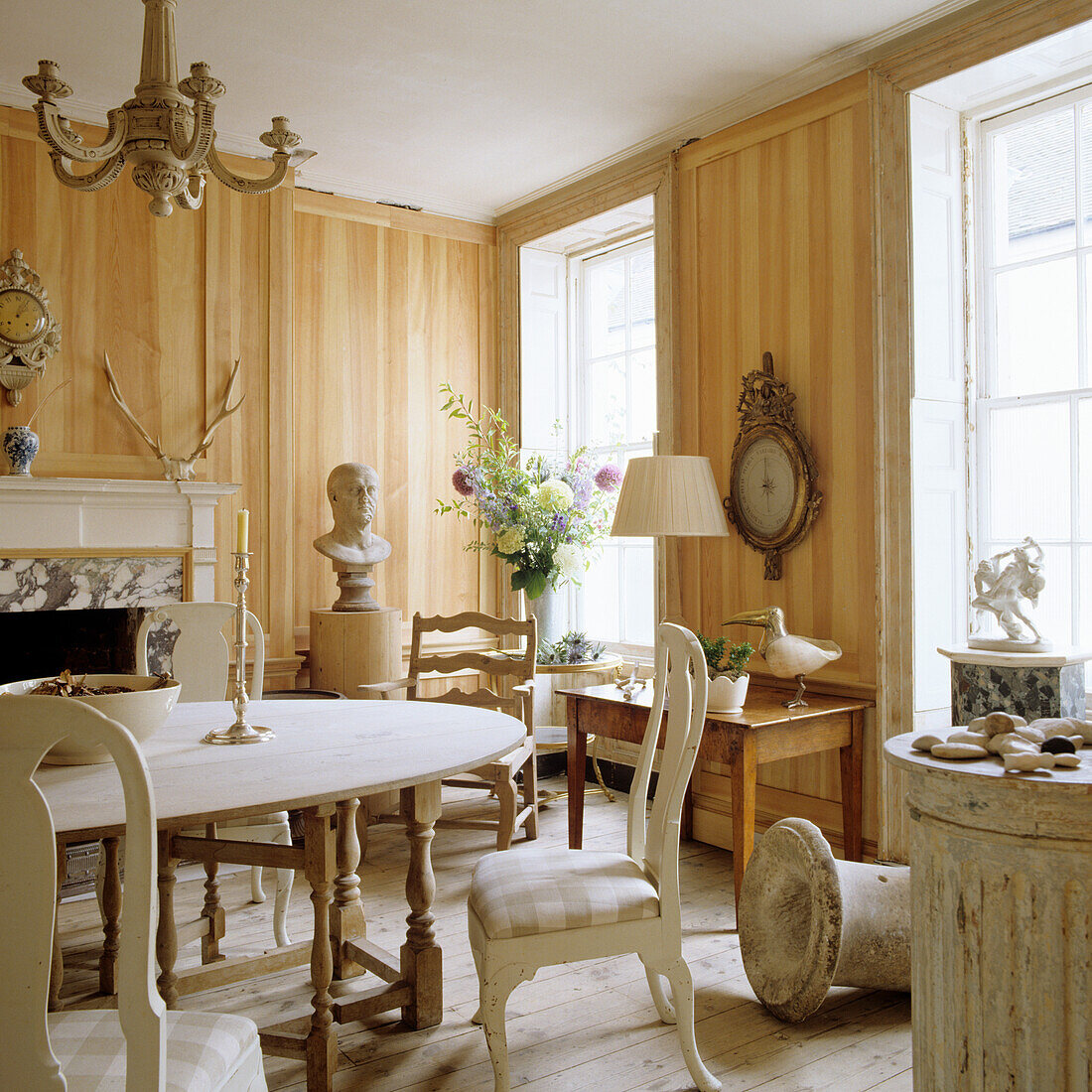 Wood-paneled dining room with antique furniture and floral decorations