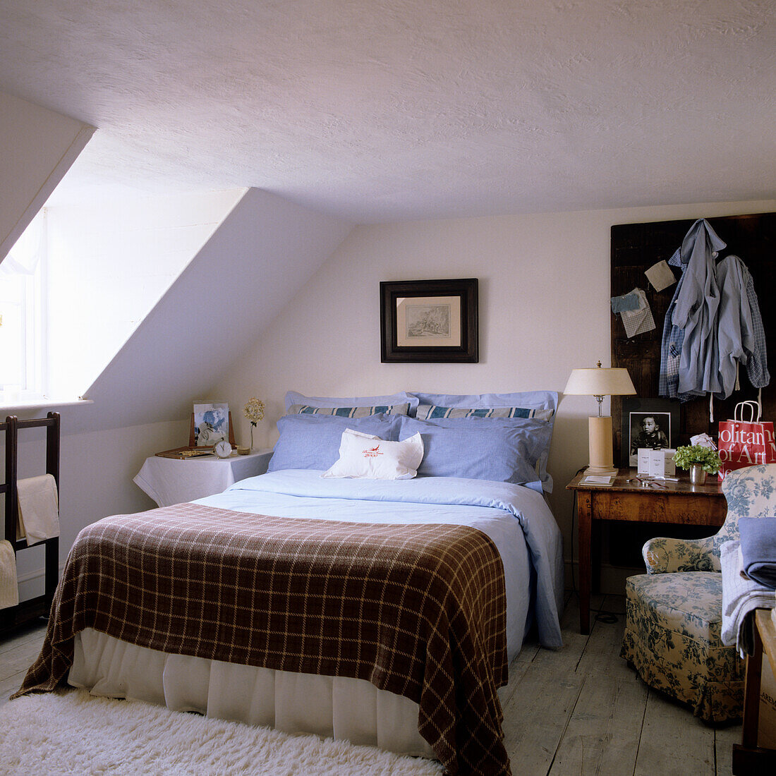 Sloped ceiling bedroom with checkered duvet cover and shades of blue blankets