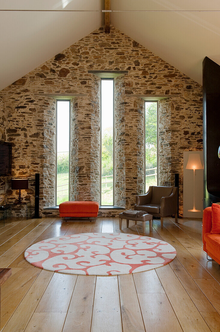 Living room with stone walls, wooden floor, patterned carpet and furniture