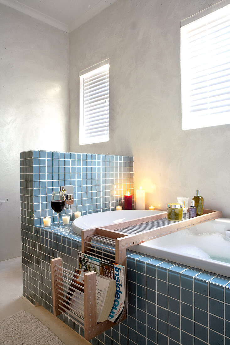 Blaue Fliesen an Badewanne mit halbhoher Wand in schlichtem Badezimmer