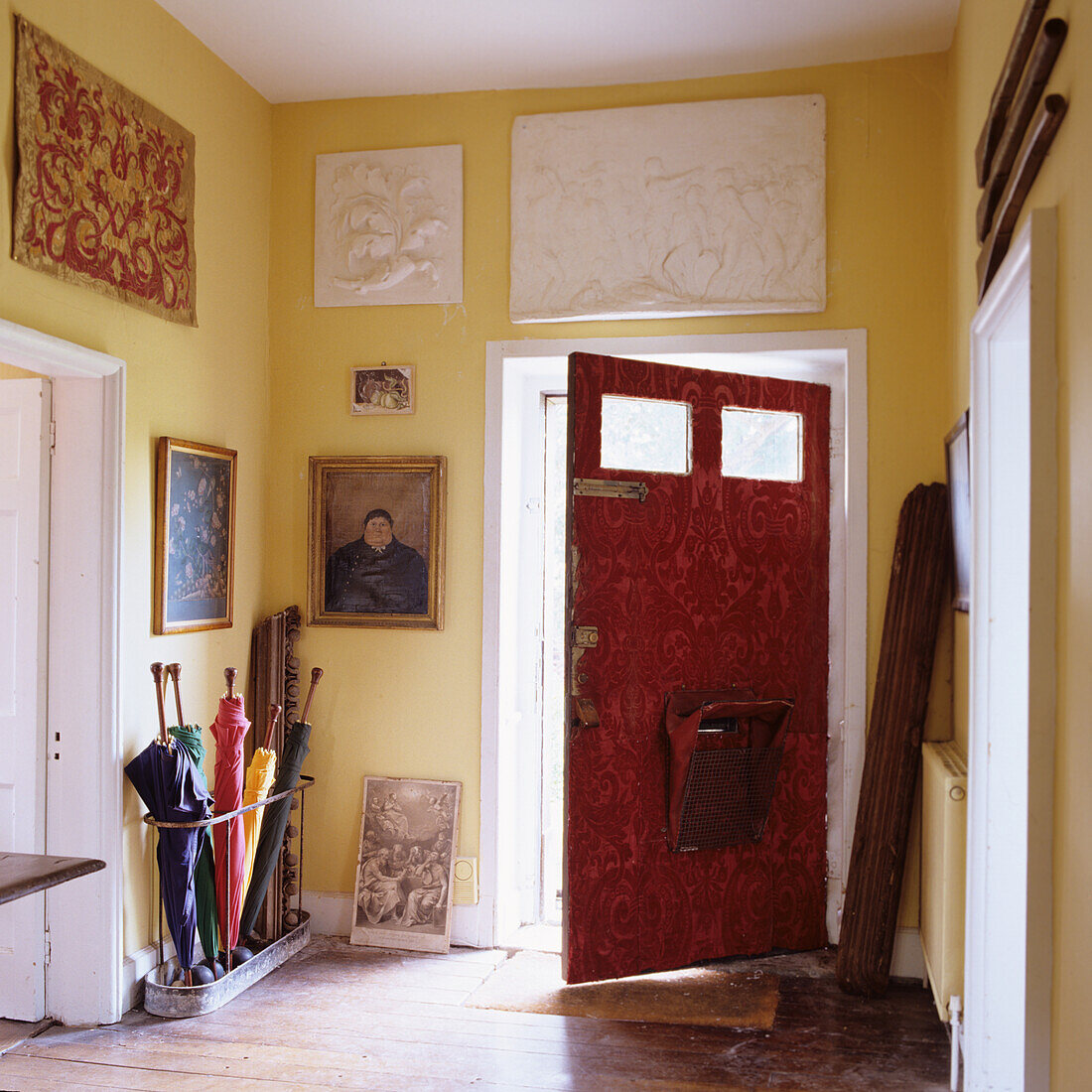 Flur mit roter Tür, gelben Wänden und diversen Kunstobjekten