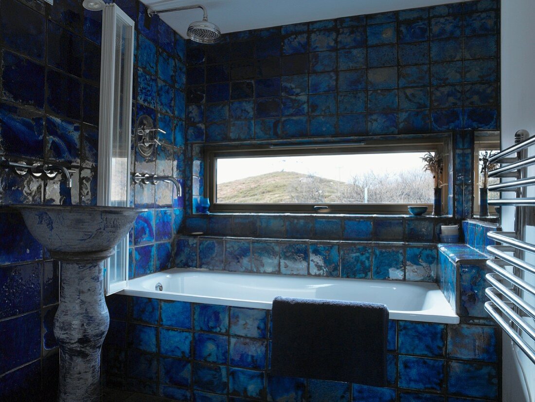 Badezimmer mit Landschaftsblick durch liegendes Fenster zwischen kräftig blau geflammten Fliesen