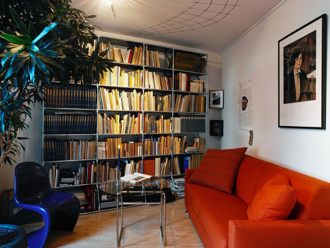 Möbelklassiker der 60er Jahre und orangefarbenes Sofa in Leseecke mit großen Pflanzen